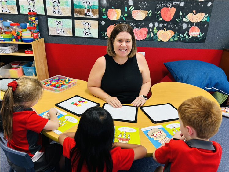 Photo of Mrs Townsend working with three students.